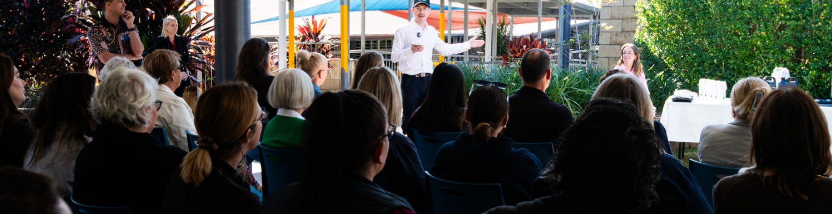 A speaker addresses seated Futures Summit attendees in an outdoor pavilion.